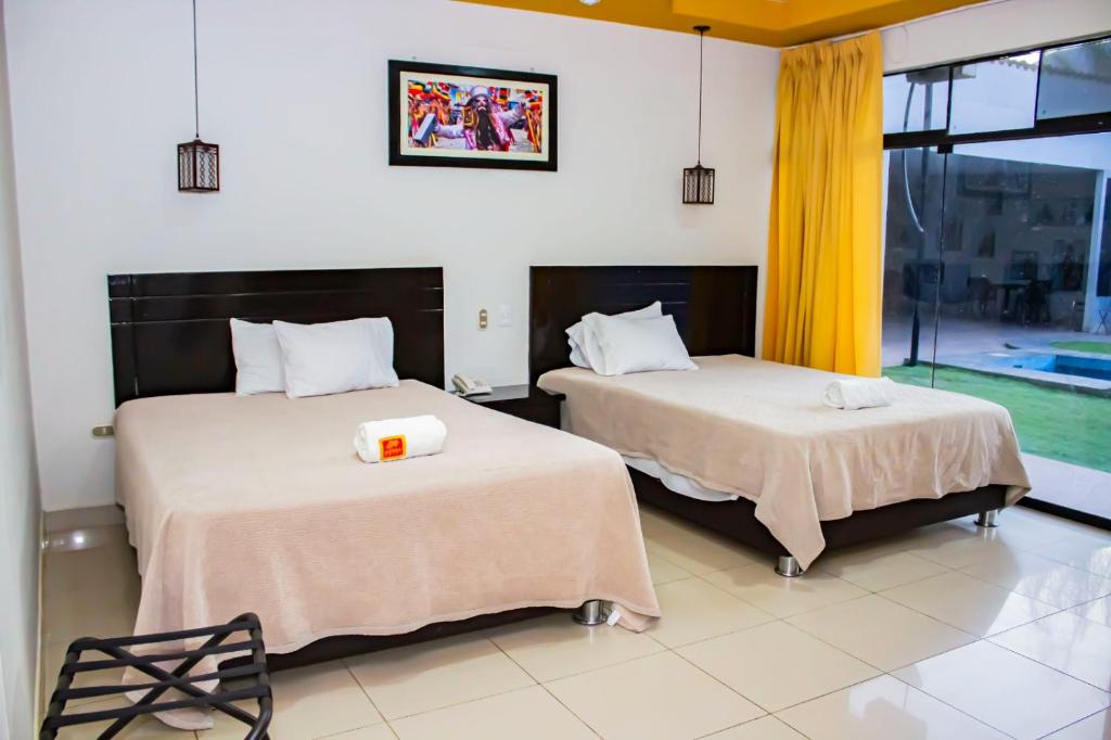 2 Betten in einem Zimmer mit Fenster in der Unterkunft La Estancia Hotel in Huánuco