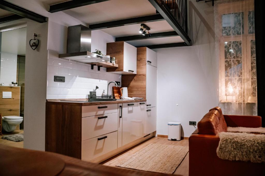 una cocina con armarios blancos y un sofá en una habitación en Apartman Saturn, en Osijek