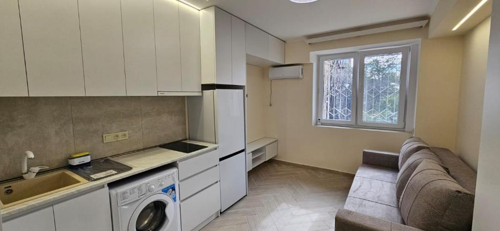 Una sala de estar con un sofá y una cocina. en Близко к метро, en Ereván