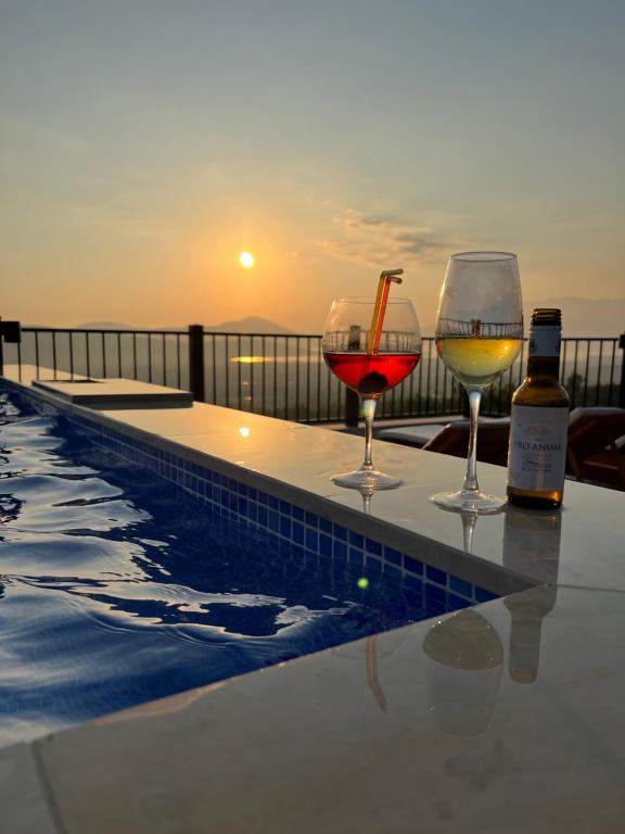 three glasses of wine sitting on a table next to a pool at Apartments HAS in Kotor