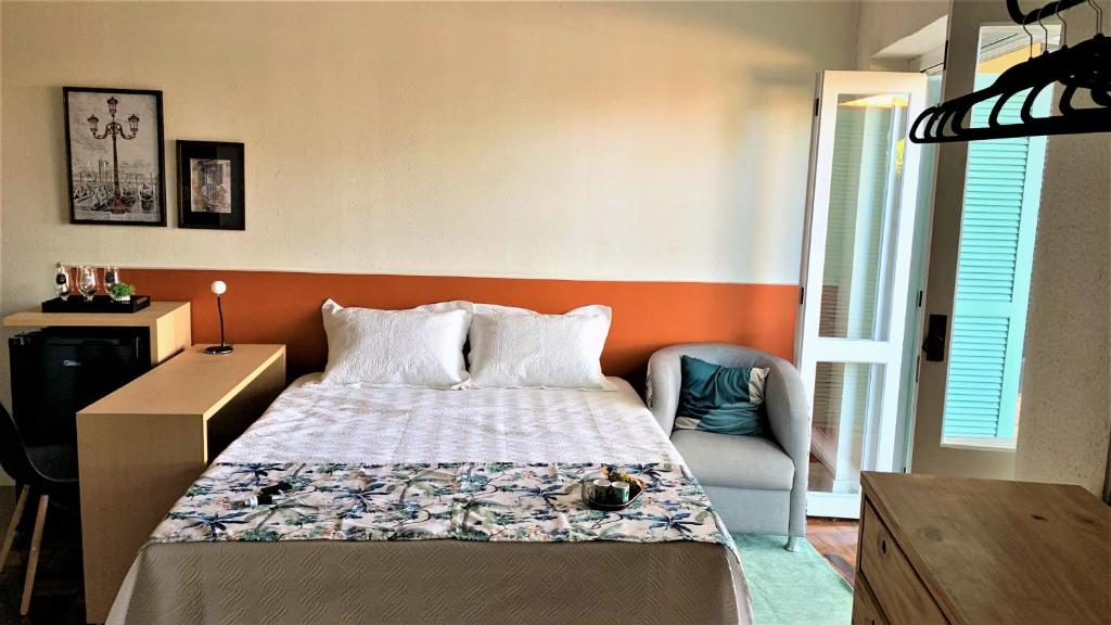 een slaapkamer met een bed, een bureau en een stoel bij Loft Veneto in Maringá