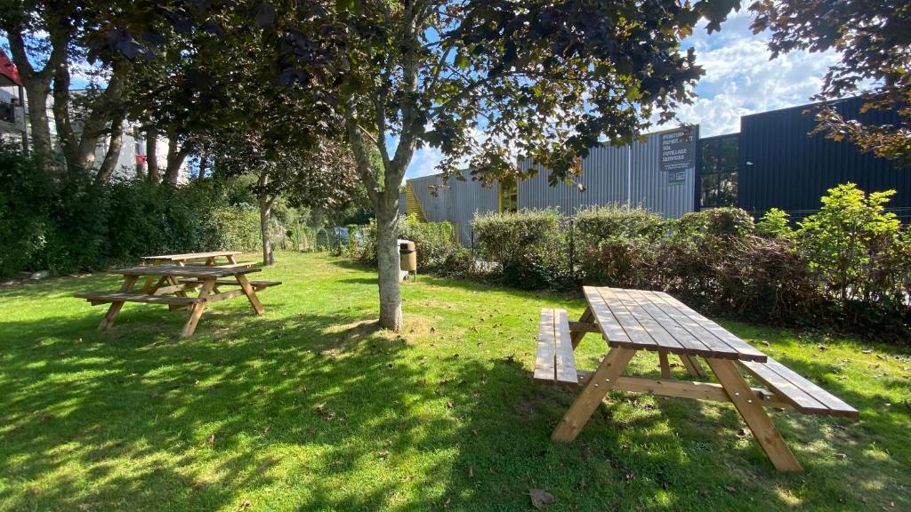 two picnic tables in the grass under a tree at Premiere Classe Quimper in Quimper