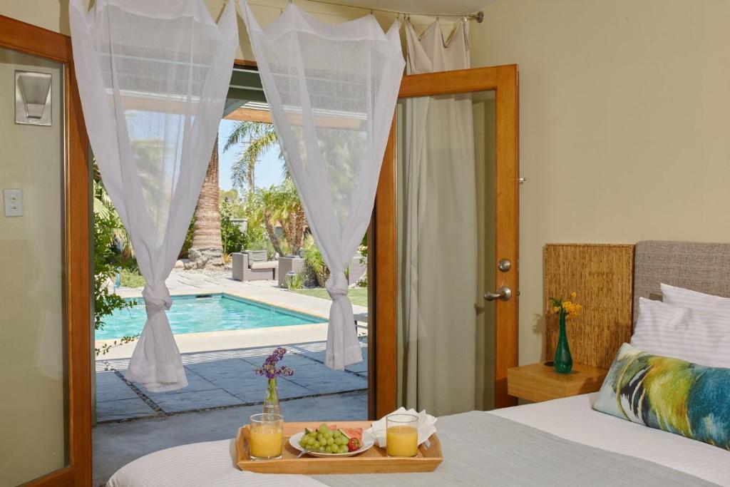 ein Schlafzimmer mit einem Bett mit einem Tablett mit Essen und einem Pool in der Unterkunft The Spring Resort & Spa in Desert Hot Springs
