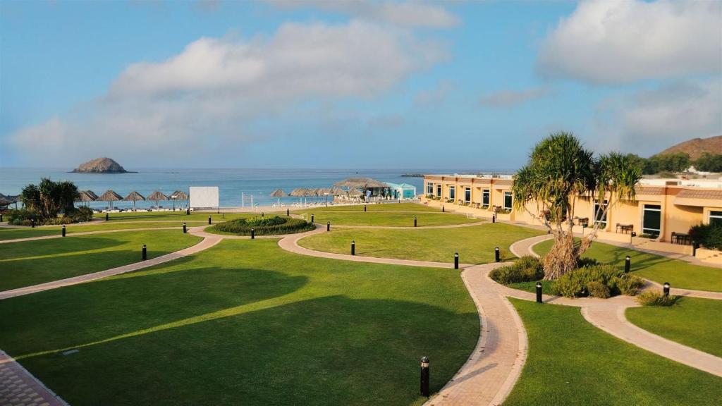 Blick auf einen Park mit dem Meer im Hintergrund in der Unterkunft Royal Beach Hotel & Resort in Dibba