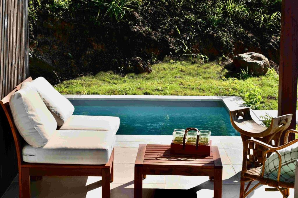 une terrasse avec un canapé, une table et une piscine dans l'établissement Les Hauteurs de Citronnelles, à Case-Pilote