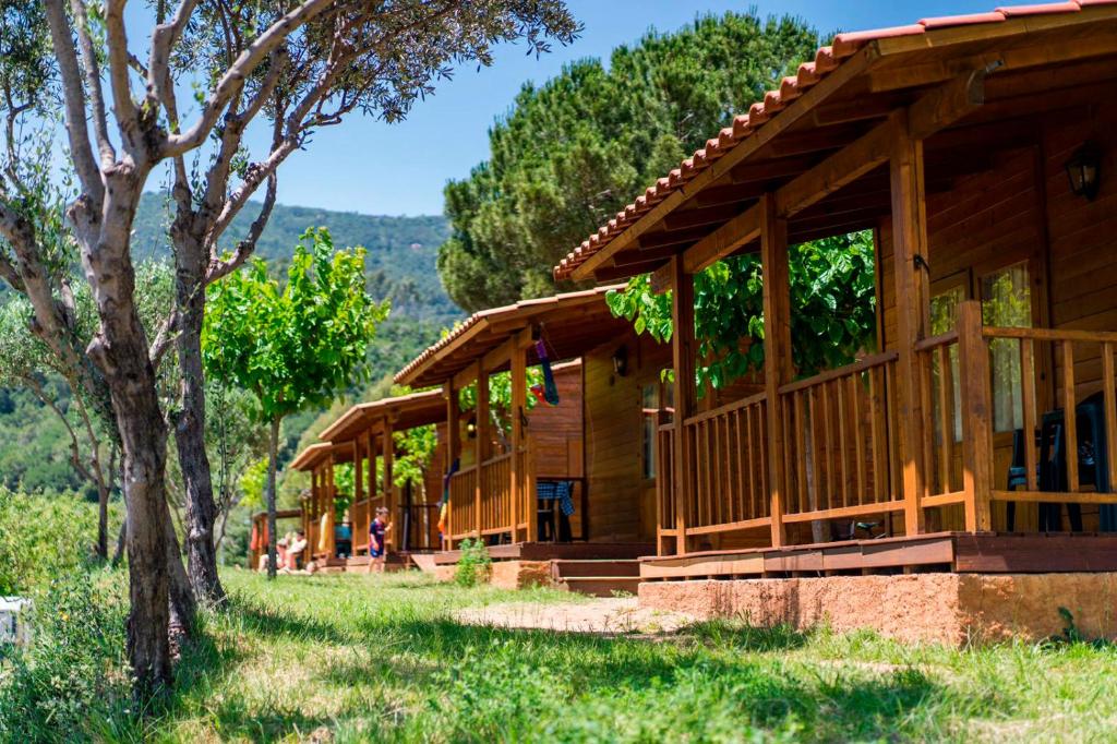 a log cabin with people sitting outside of it at Camping El Pasqualet in Caldes de Montbui