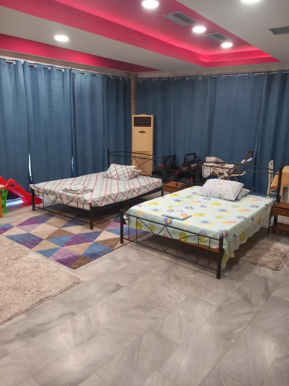 two beds in a room with blue curtains at House marios airport in Spata