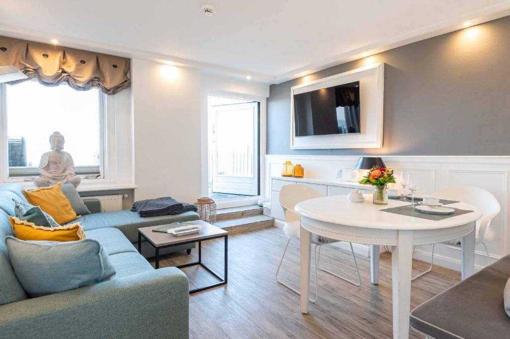 un soggiorno con un divano e un tavolo di Dünenhof zum Kronprinzen Penthouse App 115 a Wenningstedt