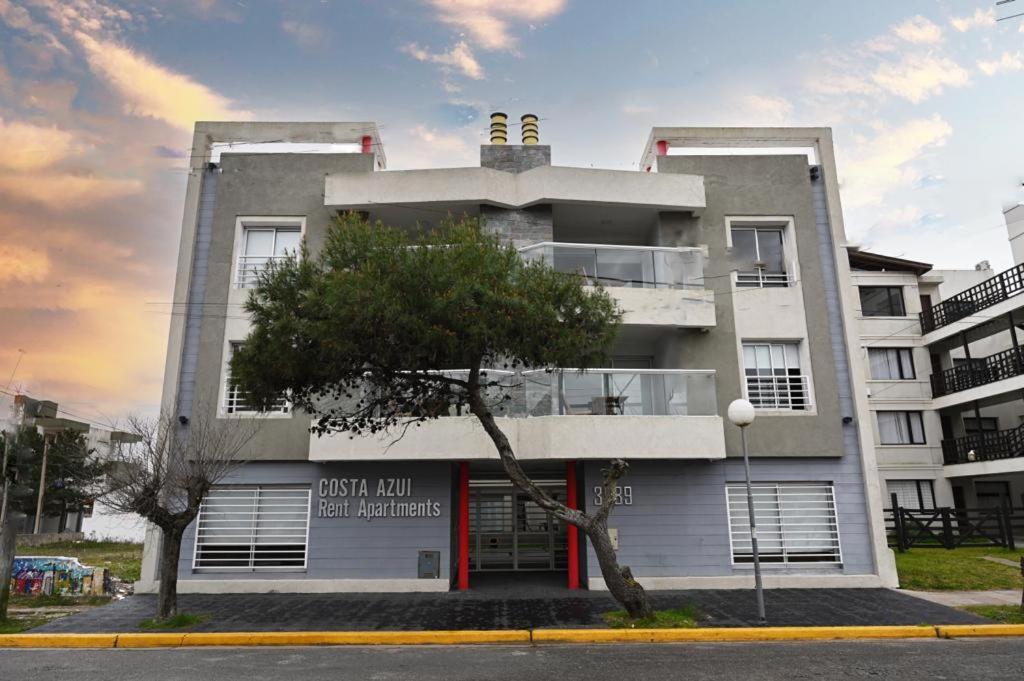 un bâtiment blanc avec un arbre devant lui dans l'établissement Costa Azul Rent Apartments, à Costa Azul