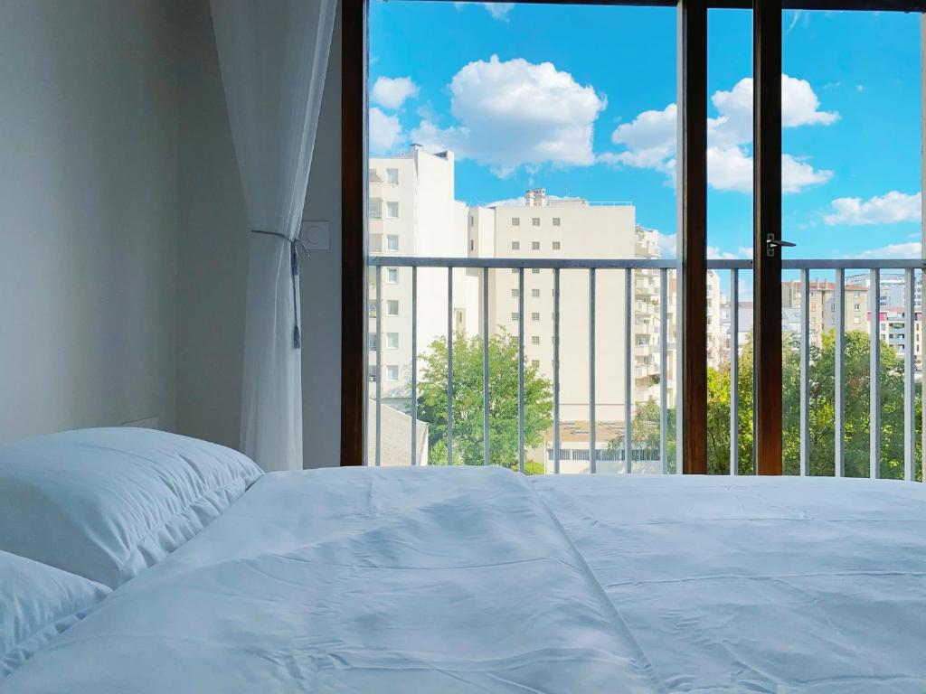 ein Schlafzimmer mit einem weißen Bett und einem großen Fenster in der Unterkunft Chez les deux garçons in Montrouge