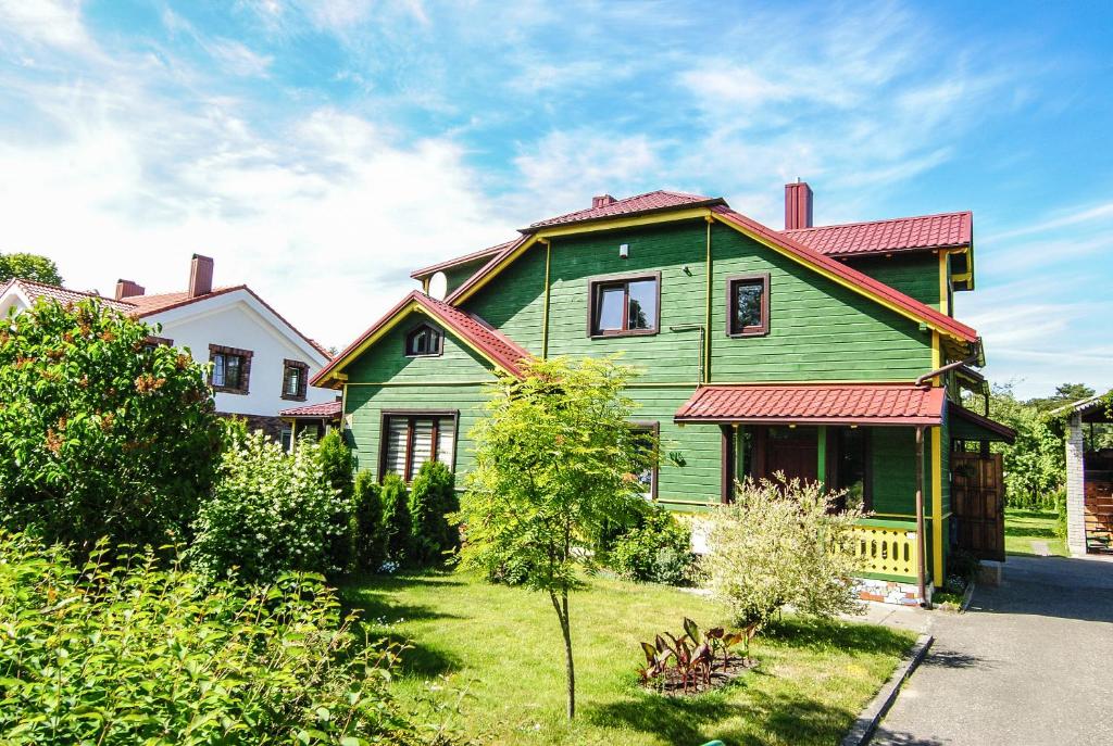 a green house with a red roof on a yard at Tourist Apartment in Klaipėda
