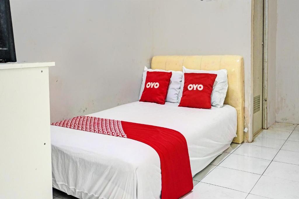 Una cama blanca con dos almohadas rojas. en OYO Life 92684 Kost Mutiara Nirwana 