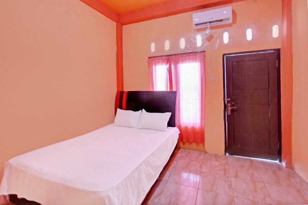 a small bedroom with a bed and a door at OYO Life 92847 Penginapan Muslim Walker in Praya