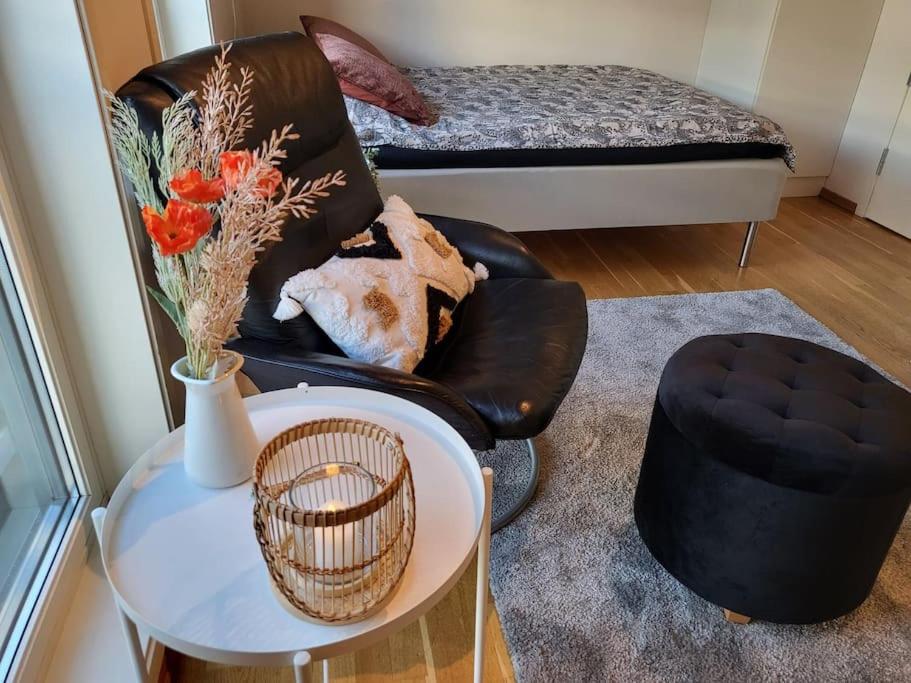 uma sala de estar com uma cadeira preta e uma mesa em One-room dorm with kitchenette, bath, bed 140x200 em Stavanger