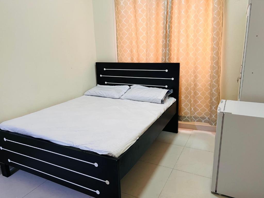 a bed with a black frame and white sheets at Cozy Studio Apartment 2 in Dubai