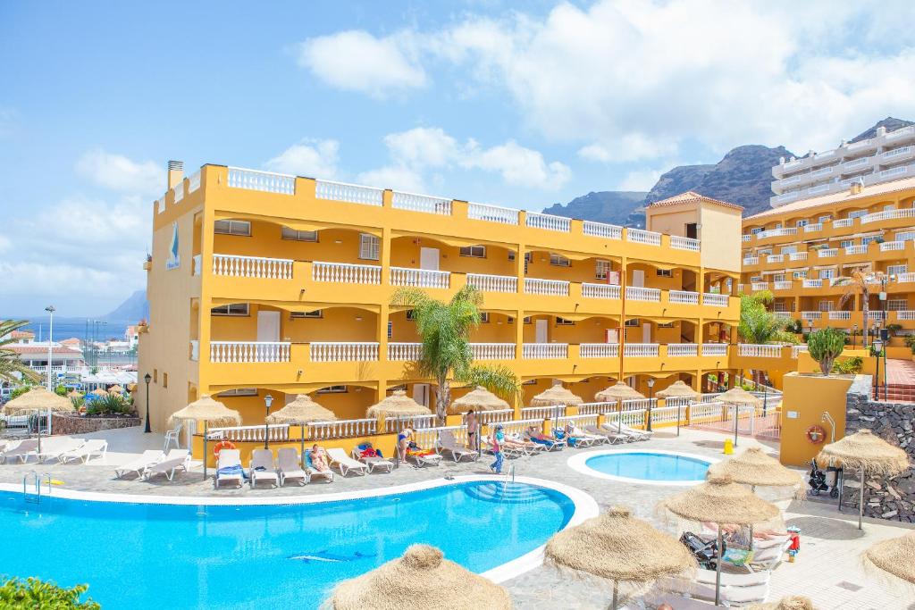 un hôtel avec une piscine, des chaises et des parasols dans l'établissement El Marques Palace by Intercorp Group, à Puerto de Santiago