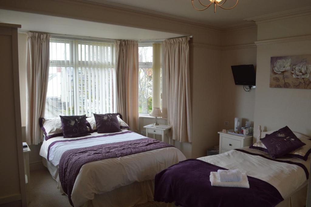 a bedroom with two beds and a window at Witchingham B&B in Holyhead