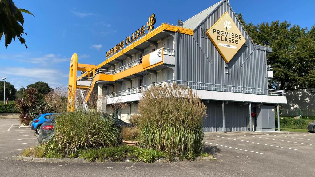 a hotel with a large yellow sign in a parking lot at Premiere Classe Quimper in Quimper