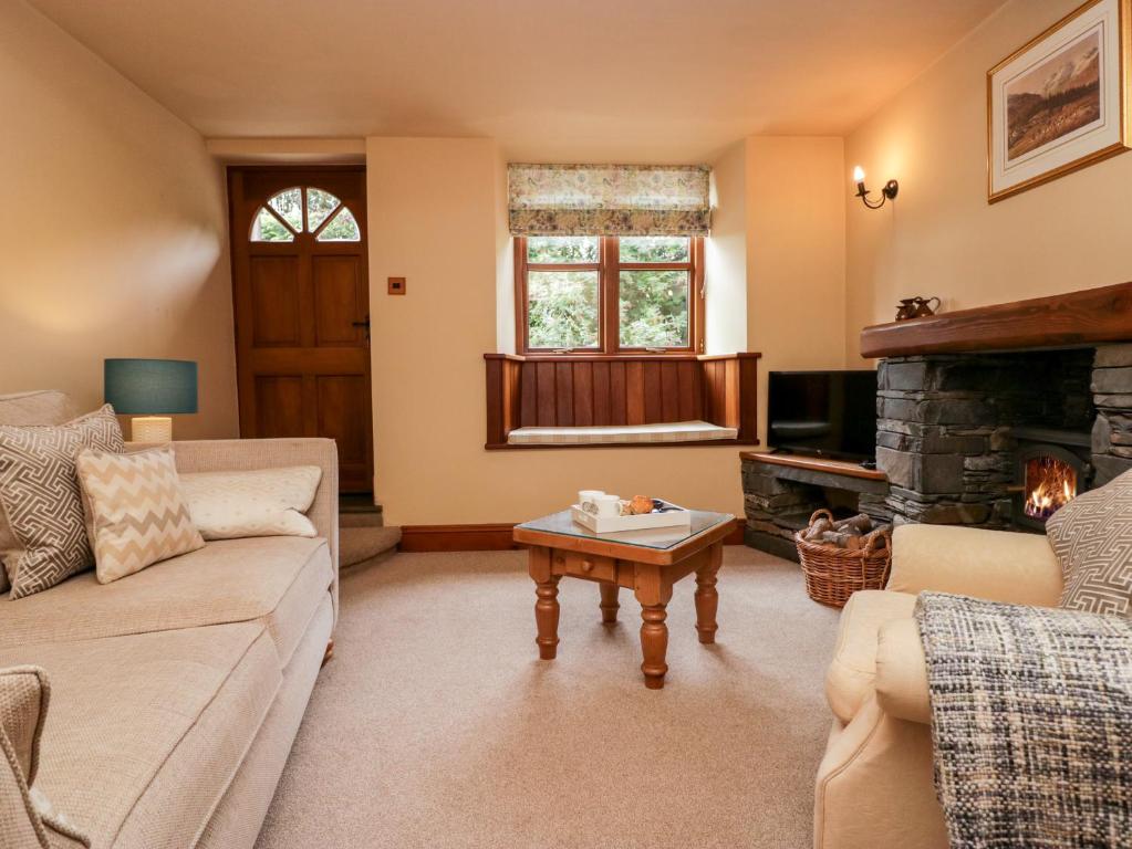sala de estar con sofá y chimenea en Huntsmans Cottage, en Ulverston