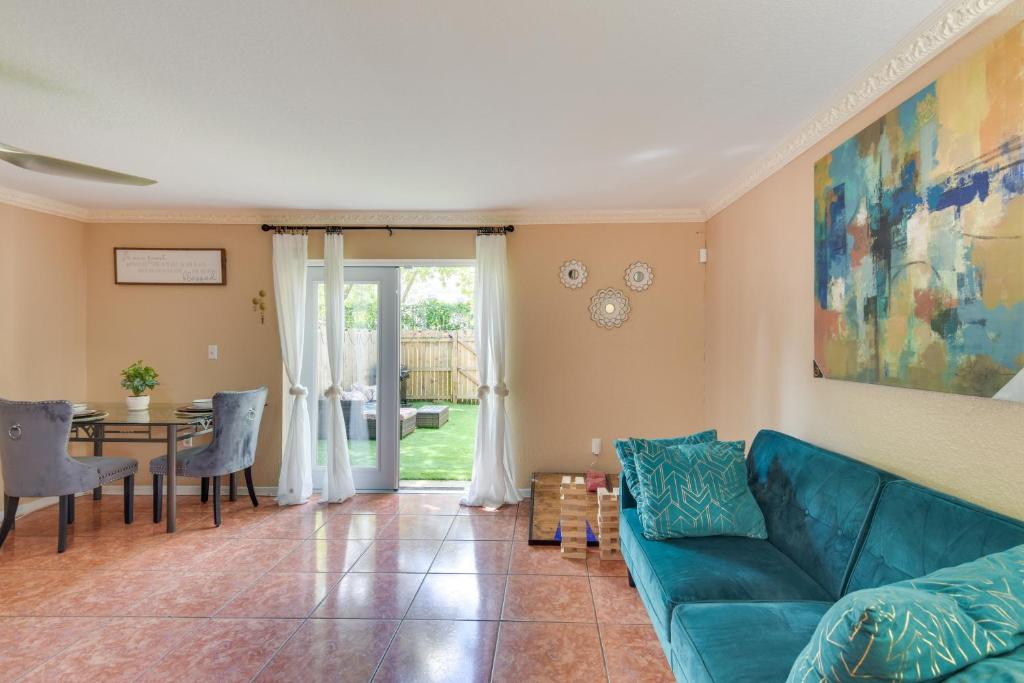 uma sala de estar com um sofá azul e uma mesa em Opa-locka Townhome, 15 Mi to Miami Beach! em Opa-locka