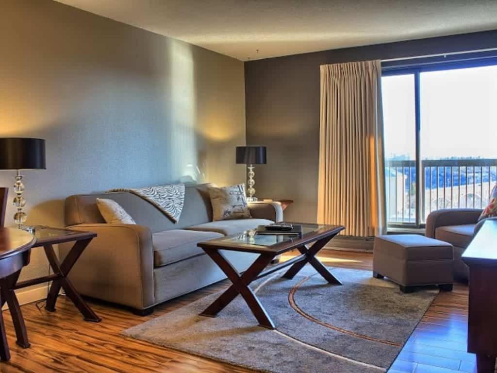 uma sala de estar com um sofá e uma mesa em Obasa Suites @ The Hallmark em Saskatoon