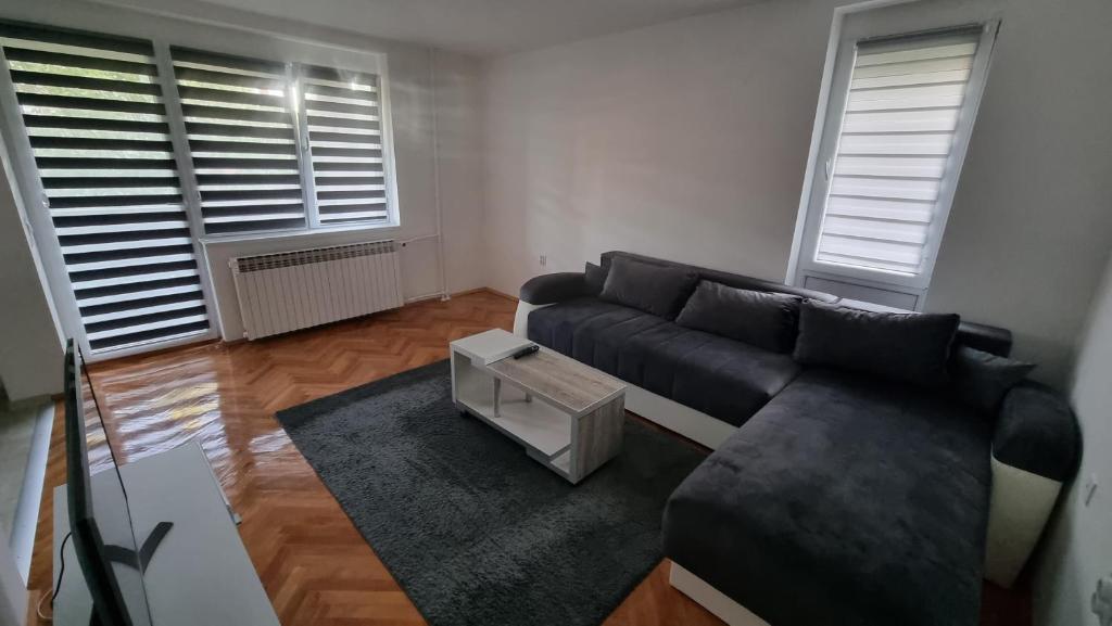 uma sala de estar com um sofá preto e uma mesa em Apartmani Vuksanović em Brestovac