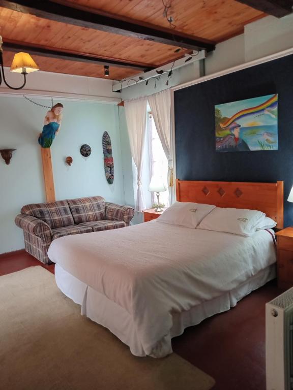 1 dormitorio con 1 cama grande y 1 sofá en Casona Patrimonial Cobquecura Hotel Boutique, en Cobquecura