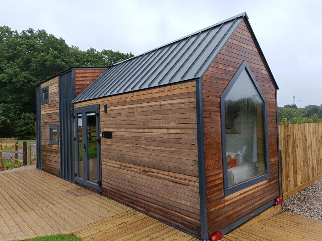 a cabin with a black roof and a wooden deck at The Tiny House in Bovey Tracey