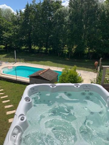 une baignoire en face d'une piscine dans l'établissement Centre de bien-être Naturéau avec massages et soins, à Chalandray