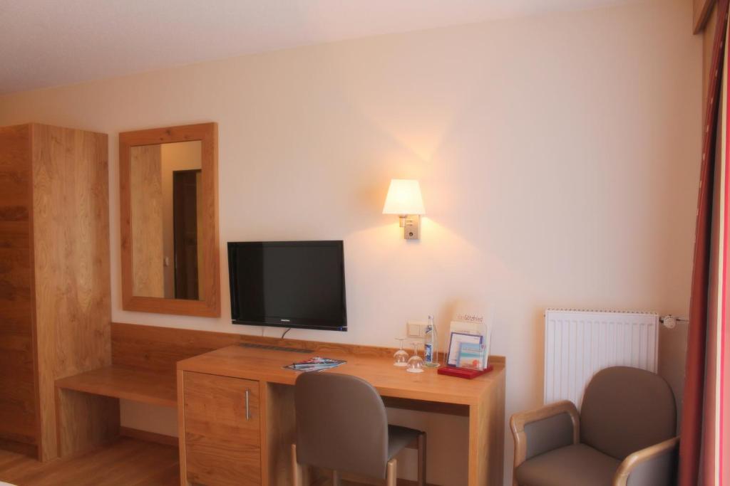 a hotel room with a desk with a television and chairs at Garden & SPA Hotel Das Götzfried in Regensburg