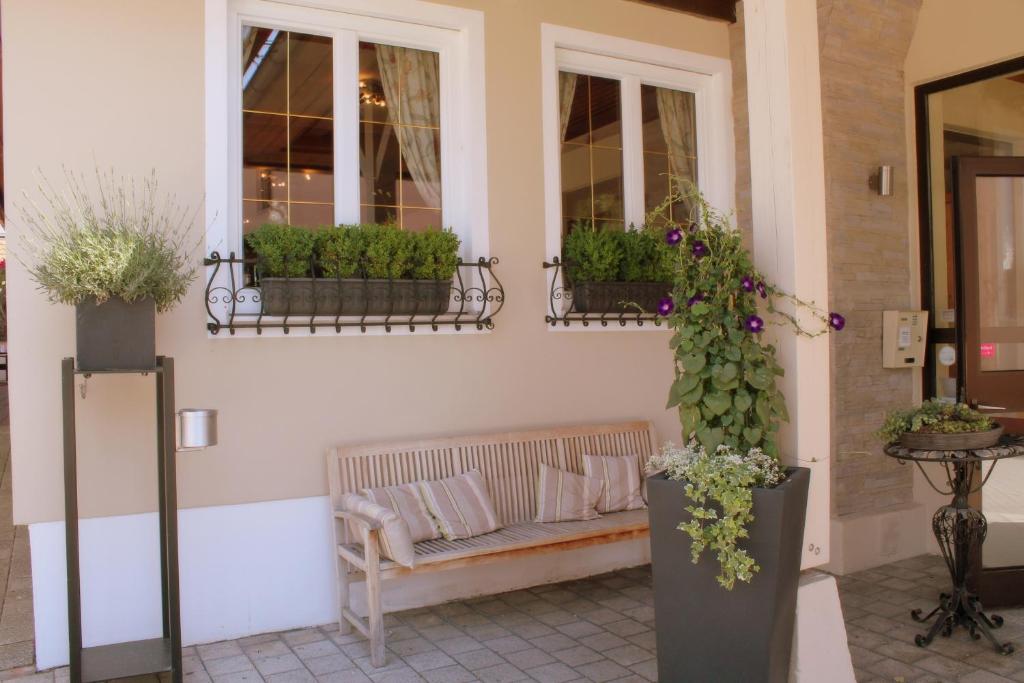 a porch with a bench and potted plants at Garden & SPA Hotel Das Götzfried in Regensburg