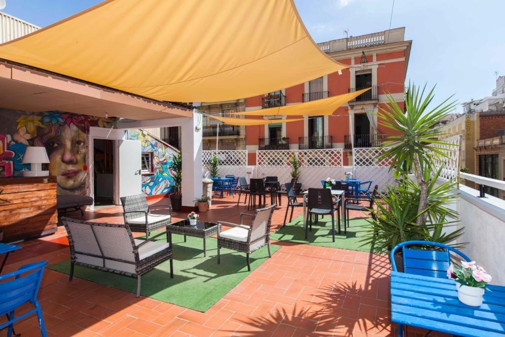 patio z krzesłami, stołami i żółtym parasolem w obiekcie The Hipstel Parallel w Barcelonie