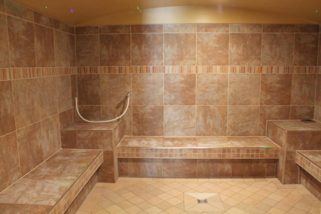 a large tiled bathroom with a tub with benches at Garden & SPA Hotel Das Götzfried in Regensburg