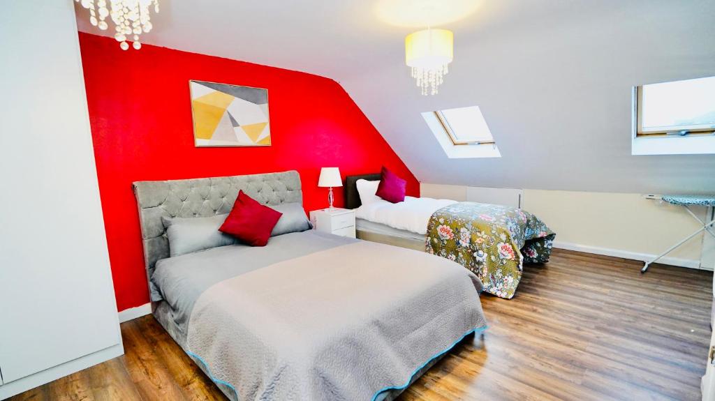 a bedroom with two beds and a red wall at E2M Stays Beautiful 6Bed Spacious House in Cranford