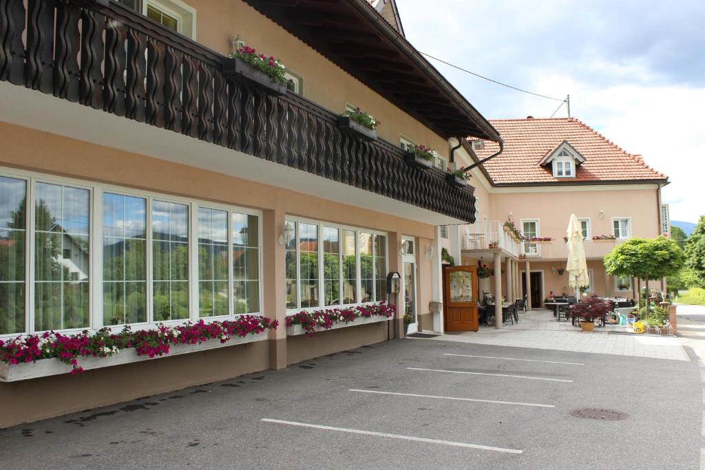 a building with flowers on the side of it at Gasthof Pension Jägerwirt in Velden am Wörthersee