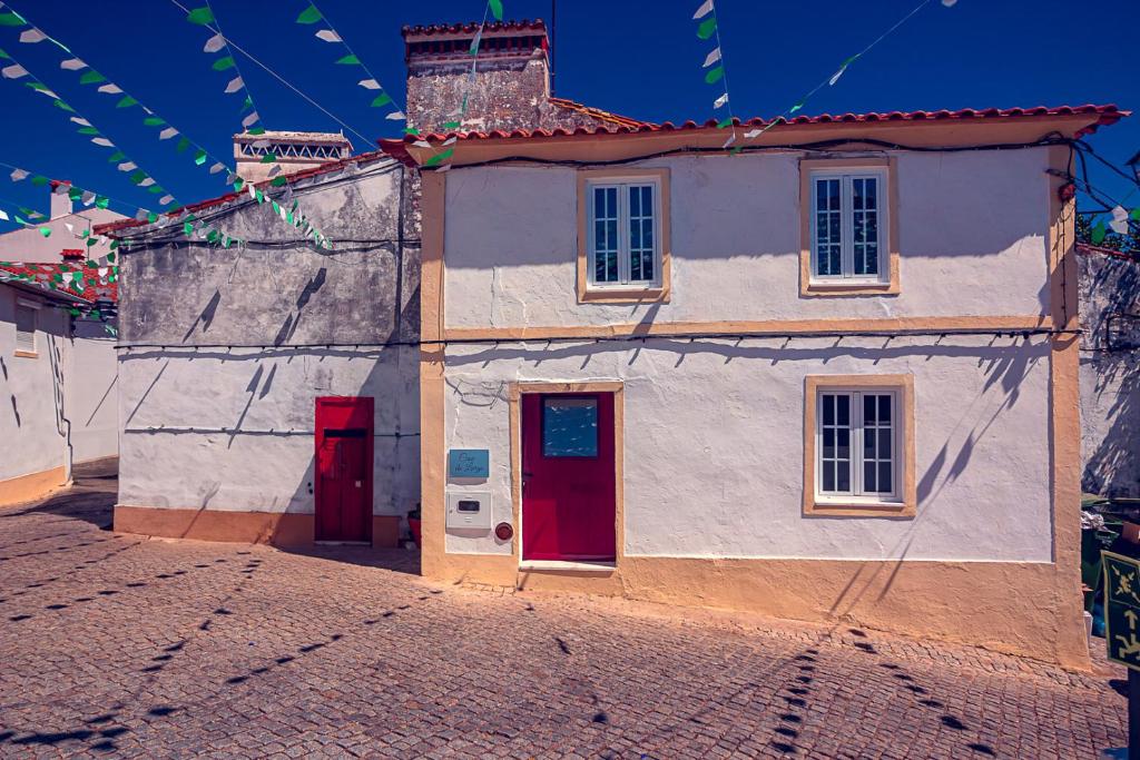 a small house with a red door on a street at Casa do Largo de NaturAlegre in Alegrete