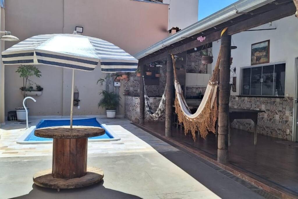 um pátio com um guarda-sol e redes de descanso junto a uma piscina em Casa de temporada Uberaba piscina em Uberaba