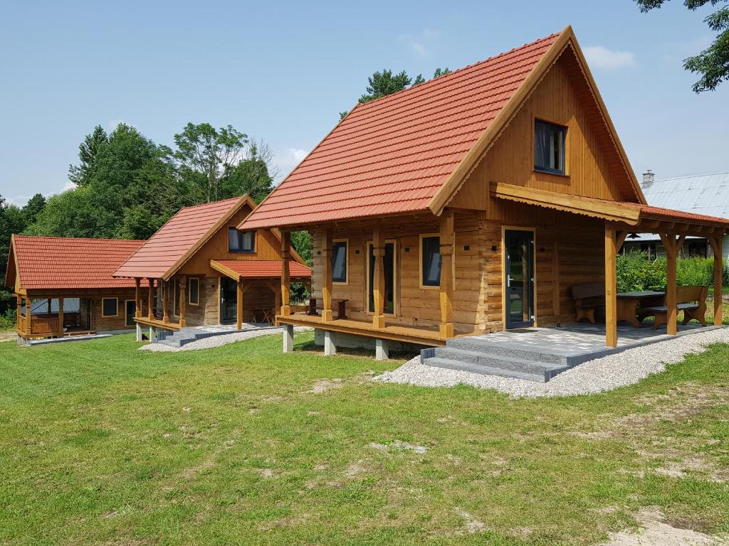 a row of wooden houses with red roofs at Kraina Biebrzy - domki nad Biebrzą in Wroceń