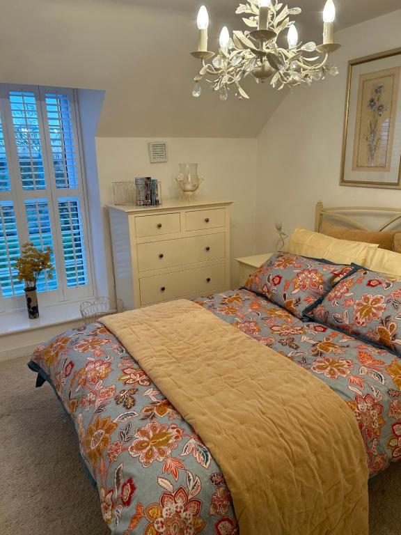 een slaapkamer met een bed, een dressoir en een kroonluchter bij Brownrigg in Otterburn