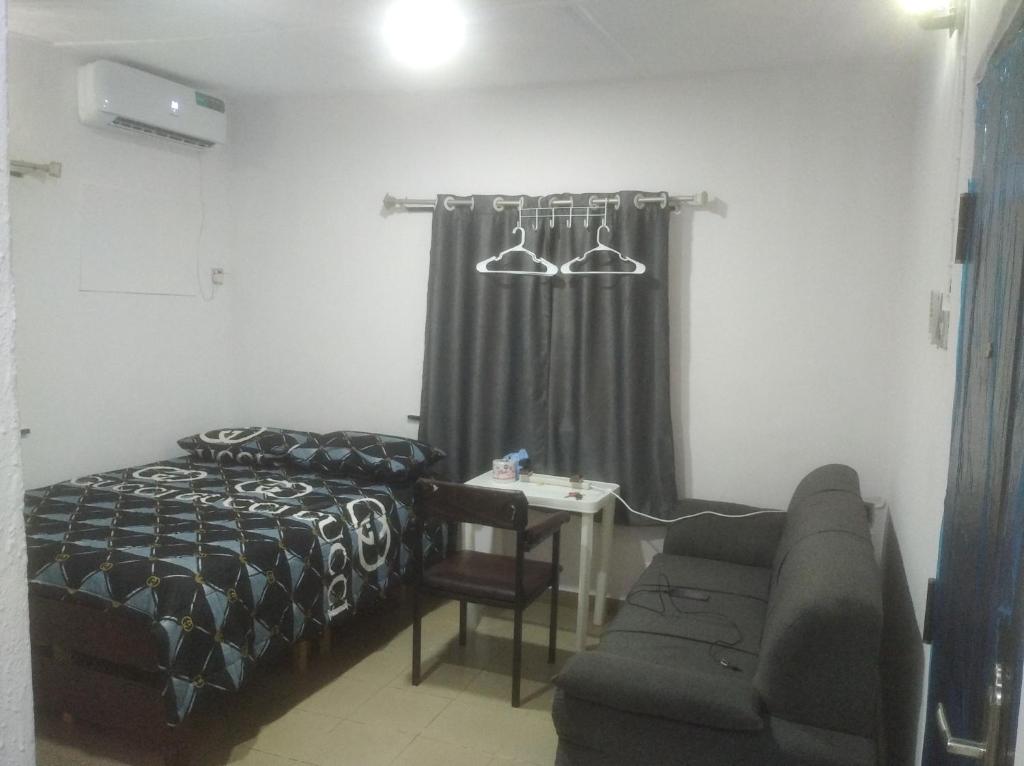 拉各斯的住宿－chinaka guest house 24hr light，一间卧室配有一张床、一张沙发和一张桌子