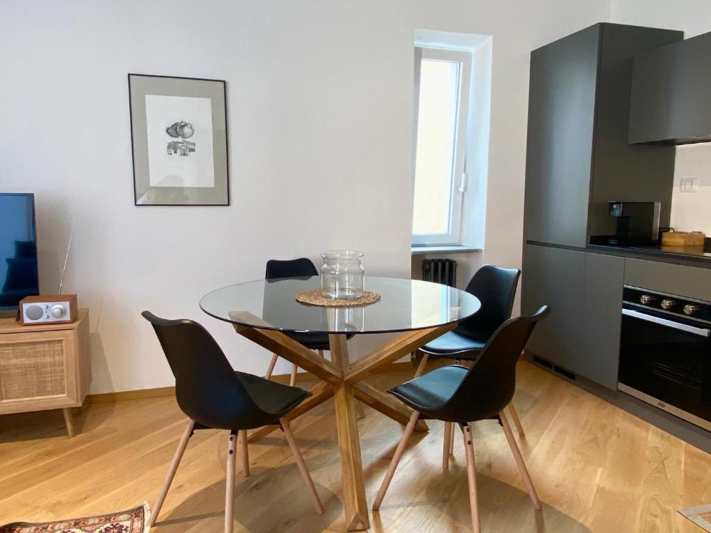 uma sala de jantar com uma mesa de vidro e cadeiras em La Casetta em Carrù