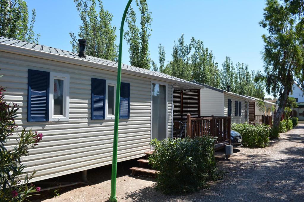 a white caravan with blue shuttered windows and a green pole at Camping Valencia el Saler in El Saler