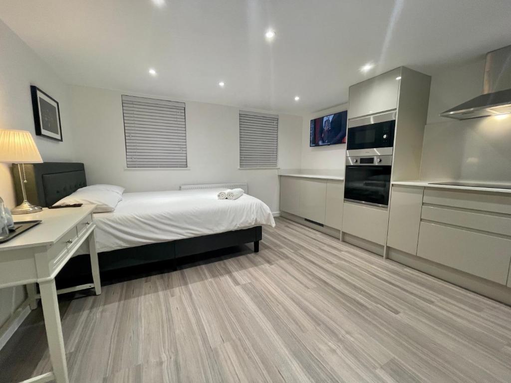 a bedroom with a bed and a desk and a kitchen at Riverside Studio Apartment Docklands E14 in London