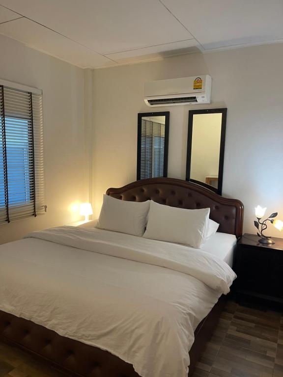 a bedroom with a large white bed with a mirror at Rynn Hotel in Trat