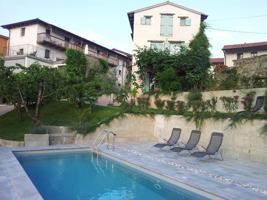 a swimming pool with two chairs next to a building at Dvor Apartments and Rooms in Dobrovo