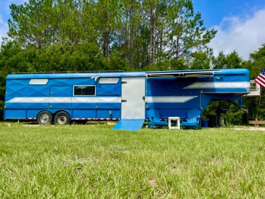 una caravana azul y blanca estacionada en un campo en NoZaDi classic horse trailer converted into a unique tiny home, 