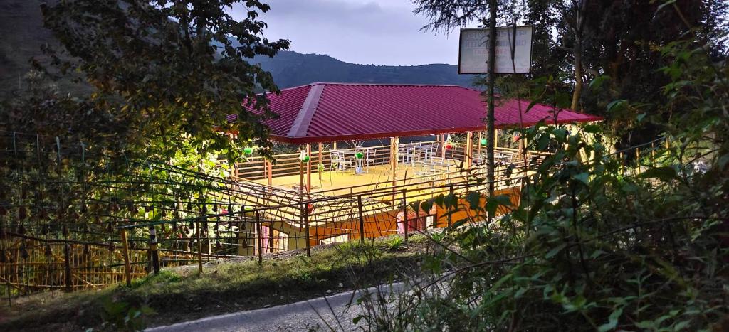 a building with a red roof and a fence at hotel chakrata green and camping in Chakrāta