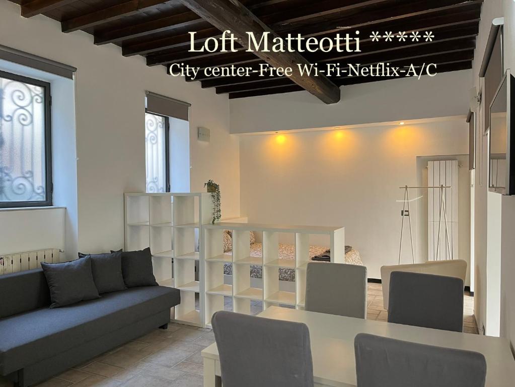 sala de estar con sofá, mesa y estanterías en Loft Matteotti - Studio in centro, en Busto Arsizio