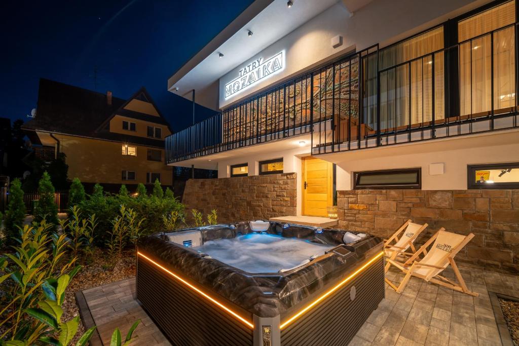 a hot tub on a patio in front of a building at Tatry Mozaika Willa PREMIUM & Sauna, Jacuzzi, Flipper by Rentilo in Zakopane