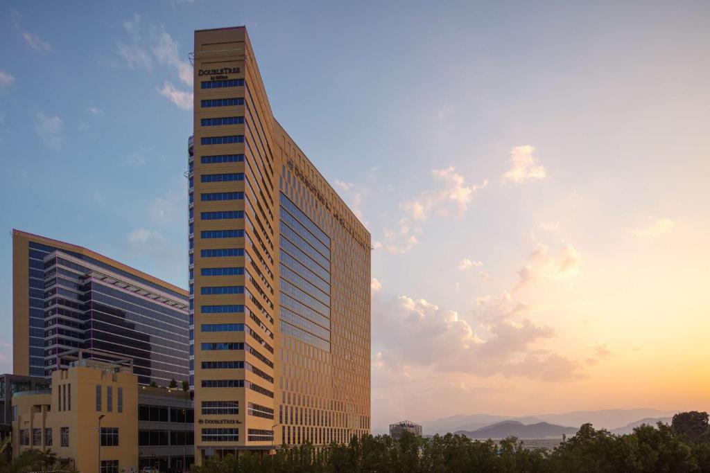 a tall building with a sunset in the background at Doubletree By Hilton Fujairah City in Fujairah